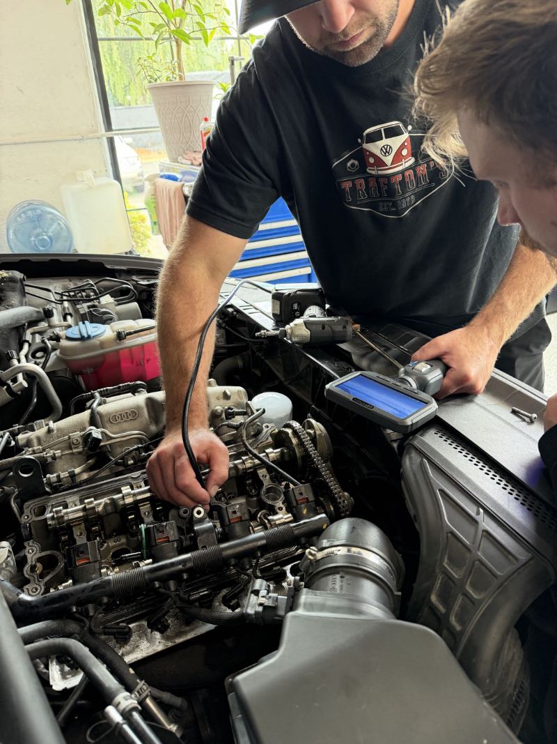 Technician using a borescope camera inside an Audi cylinder head during timing service