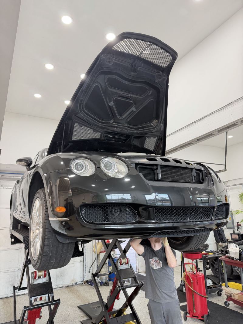 Bentley Continental raised on the scissor lift with a Trafton's technician working underneath