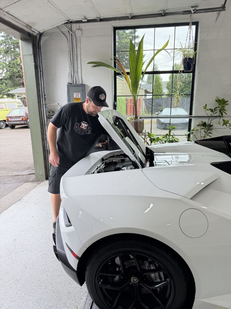 Technician inspecting the front compartment of a white Lamborghini Huracán