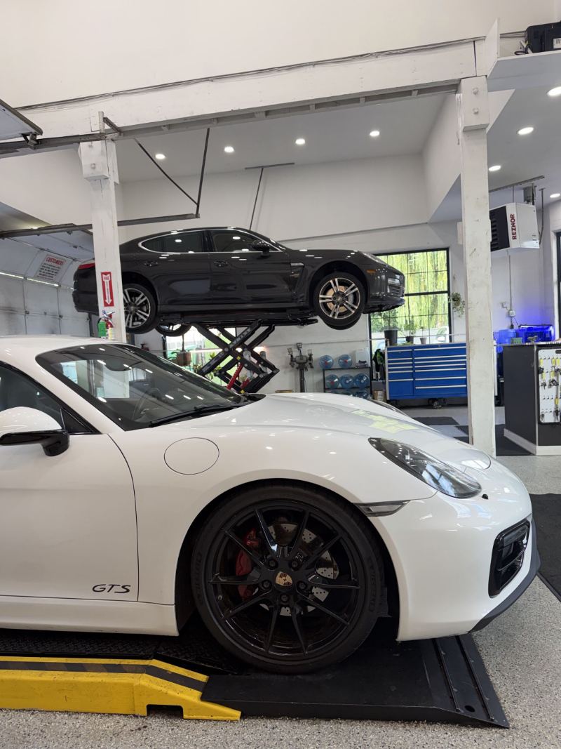 Porsche Cayman GTS beside a Panamera raised on the scissor lift at Trafton's Foreign Auto