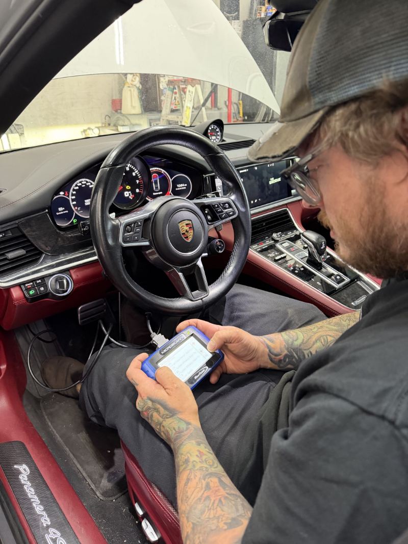 Technician running a factory scan tool inside a Porsche Panamera