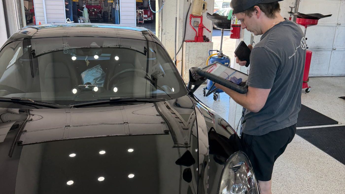 Trafton's technician documenting a pre-purchase inspection on a black Porsche with a tablet